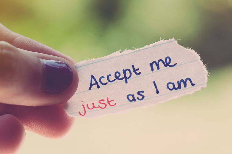 Girl holds hand-drawn message "Accept me just as I am"