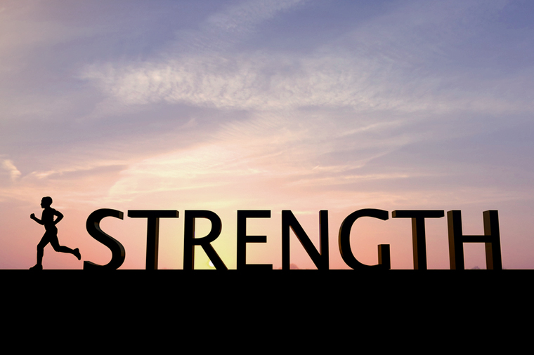 The word strength is silhouetted against a bright sunset sky. To the left of the word is a single human figure running towards the left of the image. The sky is orange at the bottom changing to blue at the top, there are some clouds in the sky.